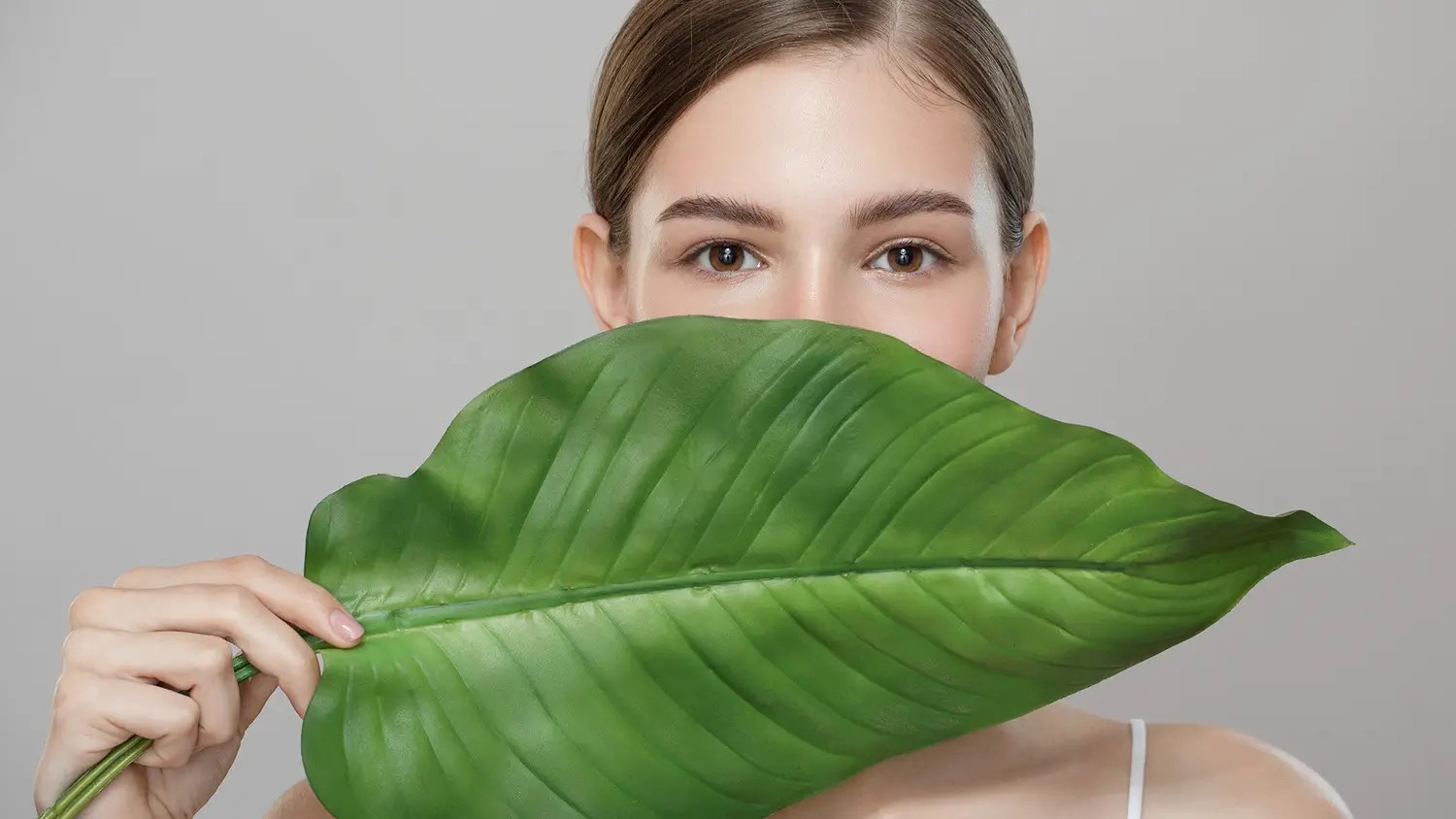 Femme appliquant une crème riche pour sa routine peau sèche hiver, dans une ambiance cocooning avec une écharpe douce.