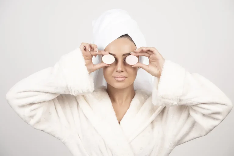 Une femme relaxée dans un peignoir blanc, appliquant un masque visage dans le cadre de sa routine spa à la maison MIHI.